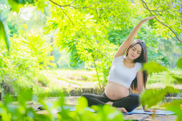 pregnant_woman_doing_yoga_exercise_nature_summer.jpg